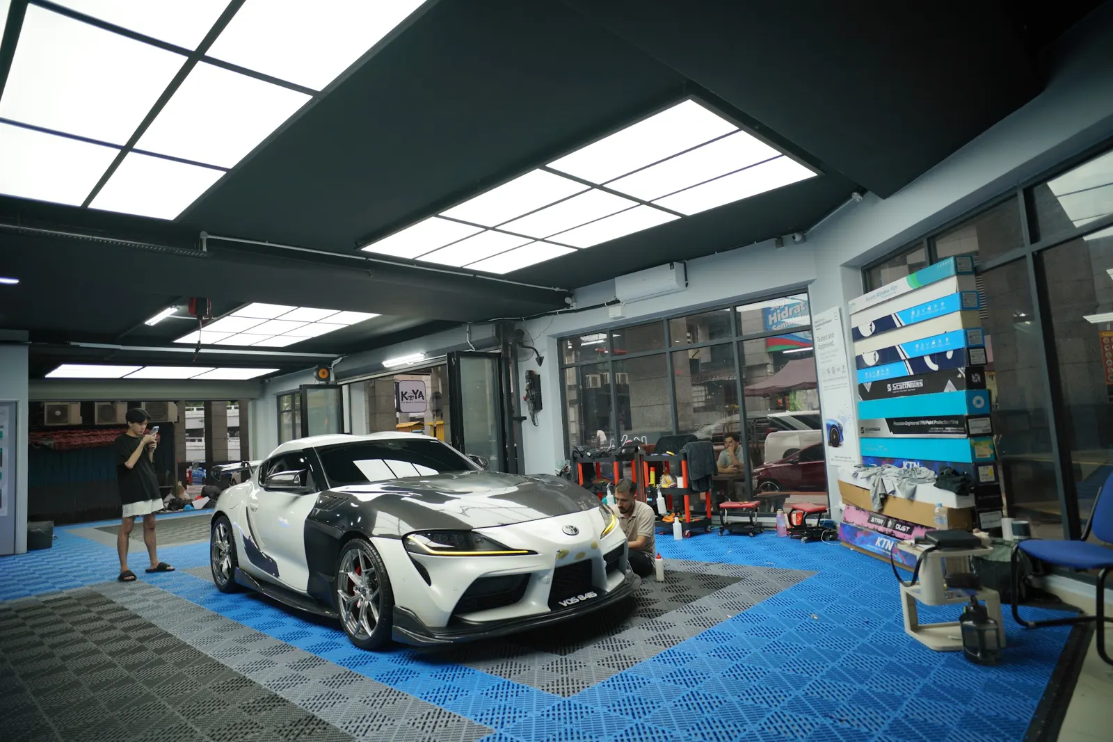 Bright KOYA detailing bay with blue tiled floor and a white Supra